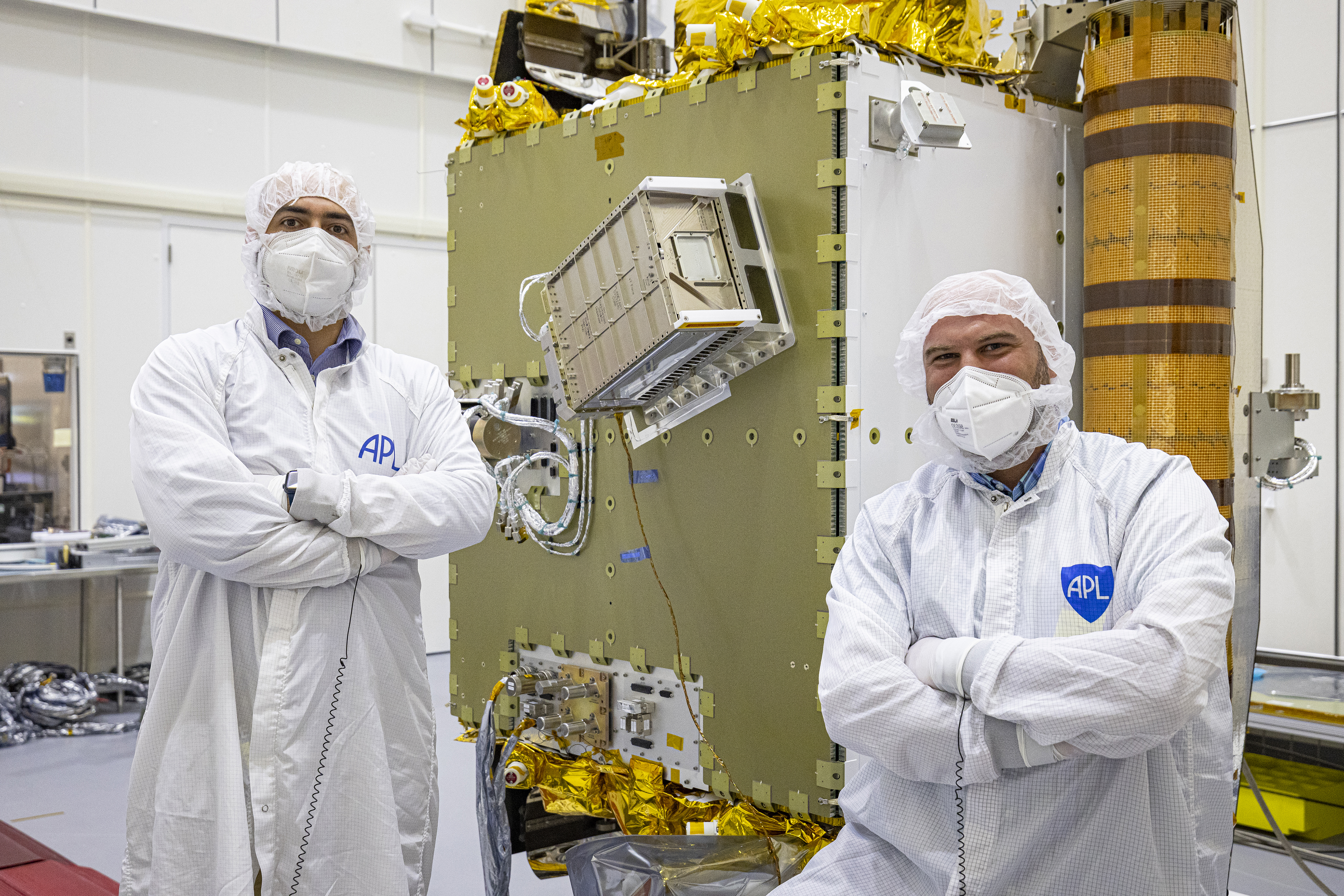 Two men in bunny suits stand with the DART spacecraft and installed LICIACube between them