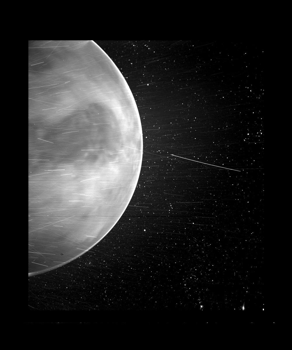 Black-and-white image of Venus with stars and streaks of light crossing in front of it