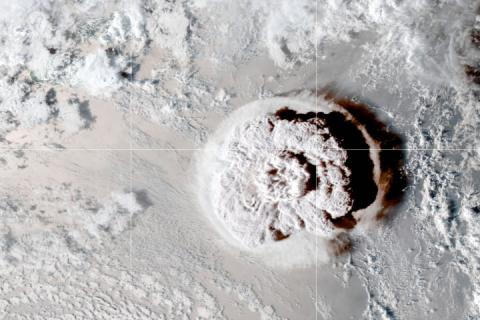 A satellite image looks down on the Hunga Tonga-Hunga Ha’apai volcano as it erupts on Jan. 15, 2022, with clouds surrounding a circular cloud of vapor and debris