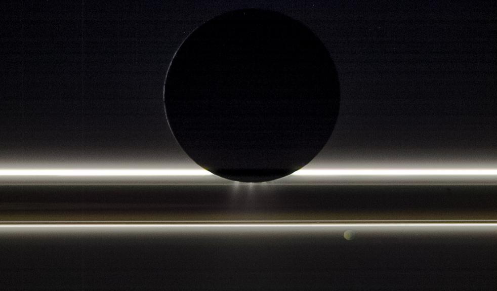 Image of Enceladus silhouette and geysers over Saturn's rings